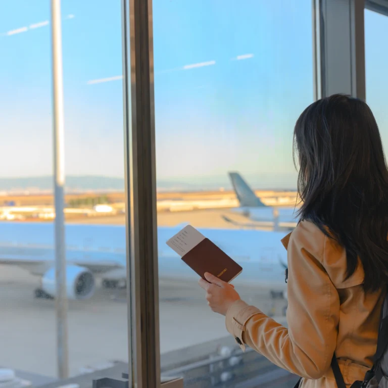 femme a l'aeroport, tenant son passeport à la main et observant un avion à l'arrêt